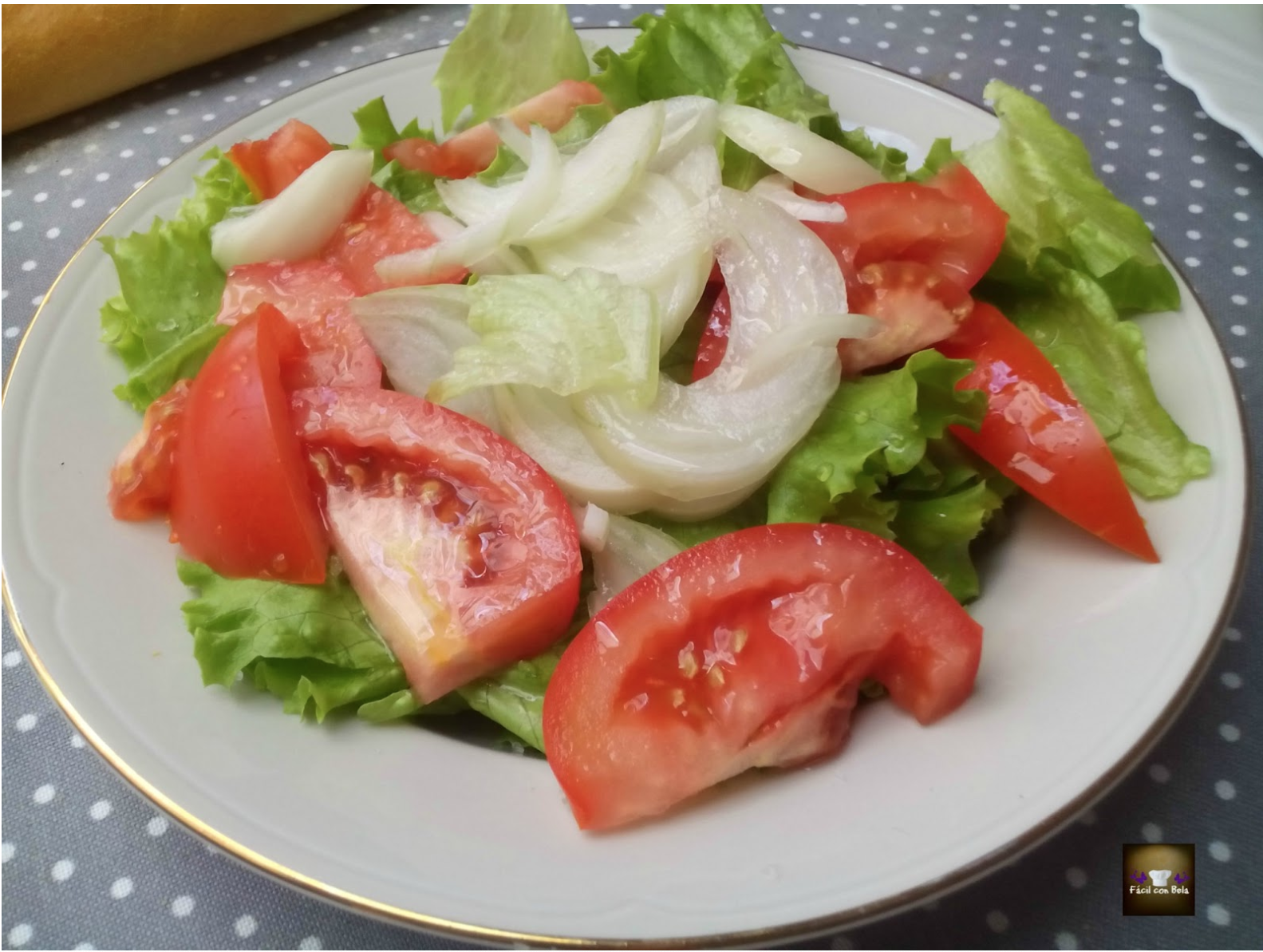 Ensalada de lechuga con cebolla y tomate con conejo al ajillo.